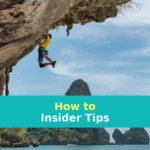 man climbing cliff beside beach