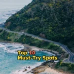 gray asphalt road beside mountain surrounded by green leafed trees during daytime