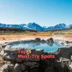 brown field near mountain under blue sky during daytime