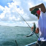 man in white t-shirt holding a fish